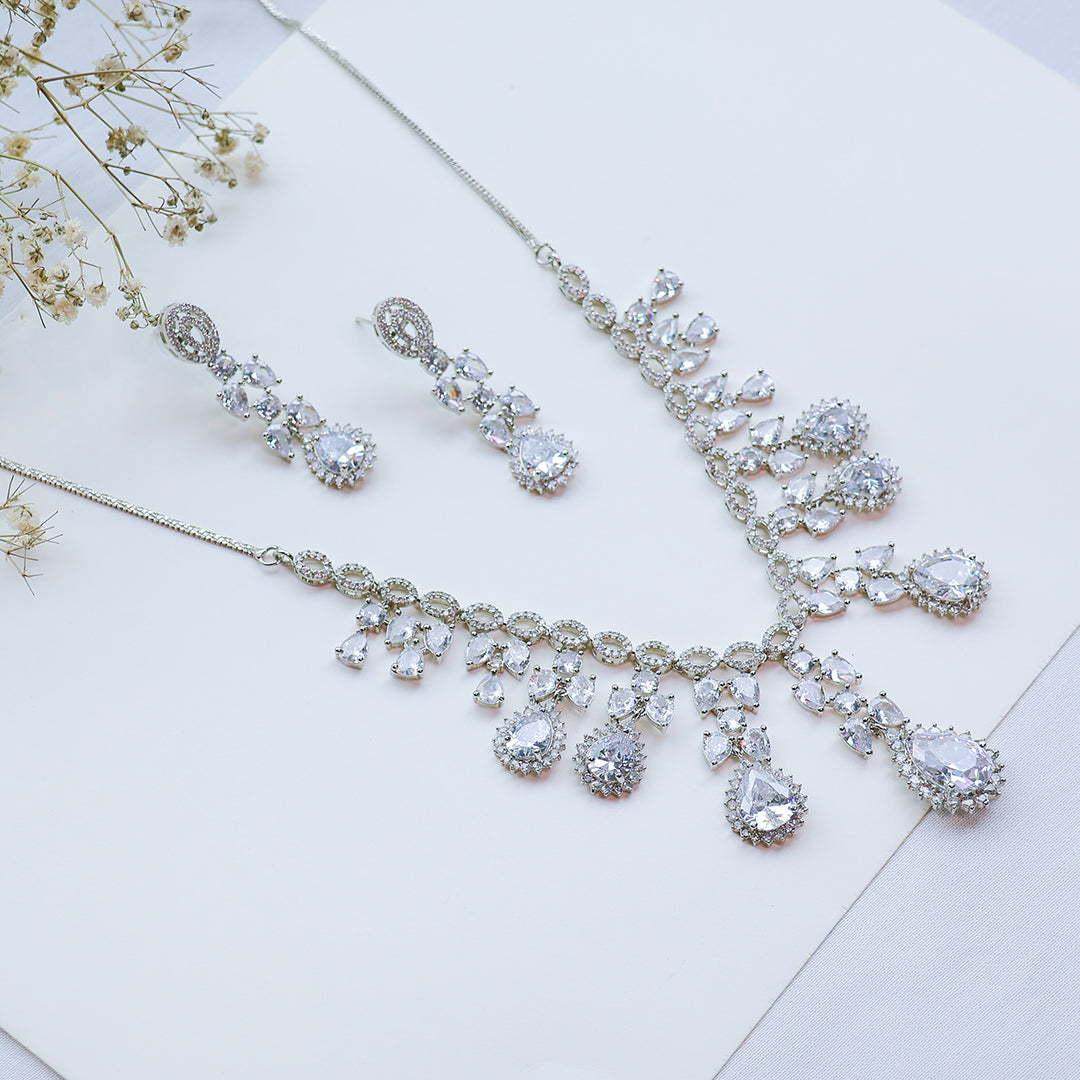 Silver jewelry set with necklace and earrings on a light background