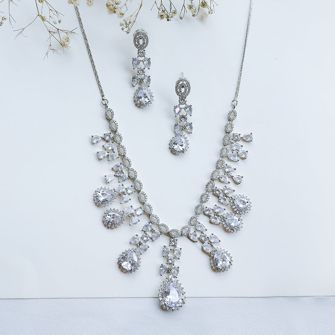 Silver necklace and earrings set on a light background