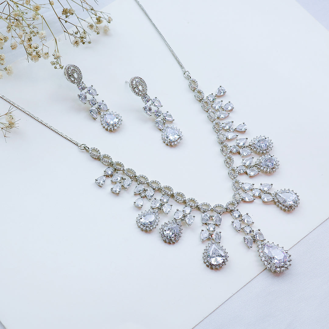 Silver necklace and earrings with clear stones on a light background