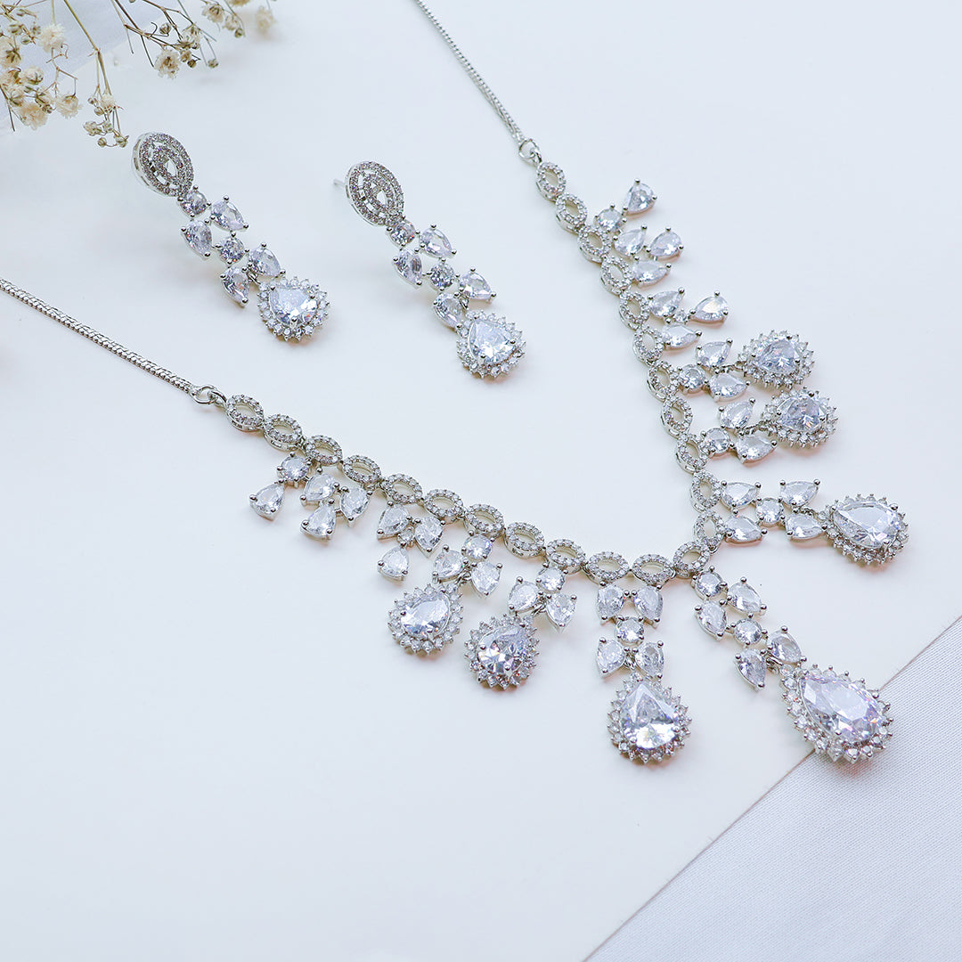 Silver necklace and earrings set on a light background