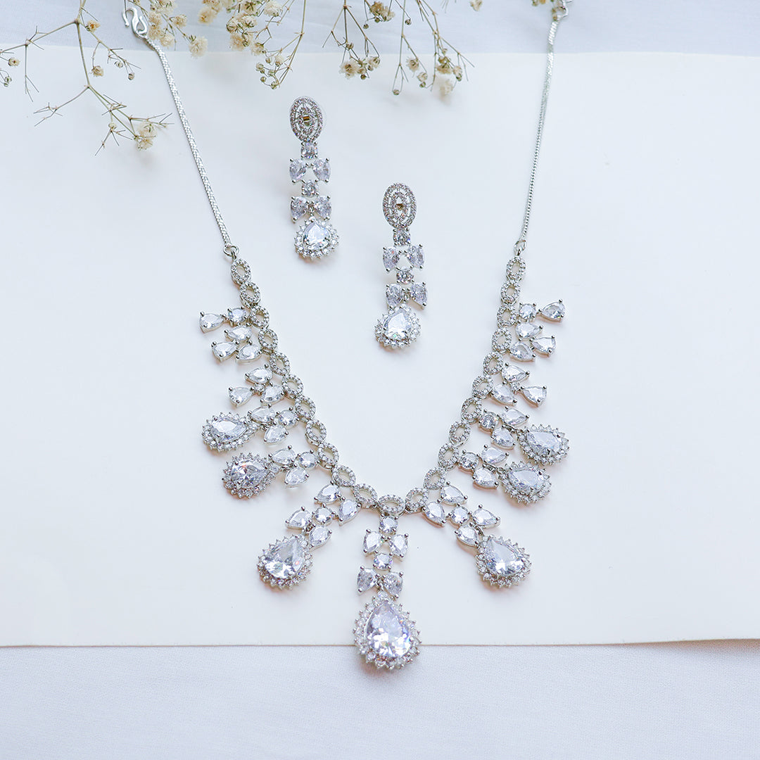 Silver necklace and earrings with clear stones on a white background