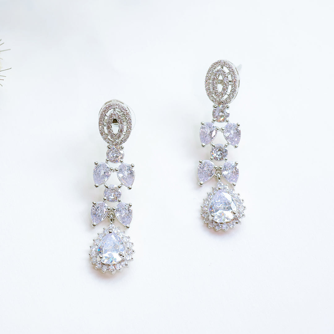 Pair of silver earrings with clear gemstones on a white background