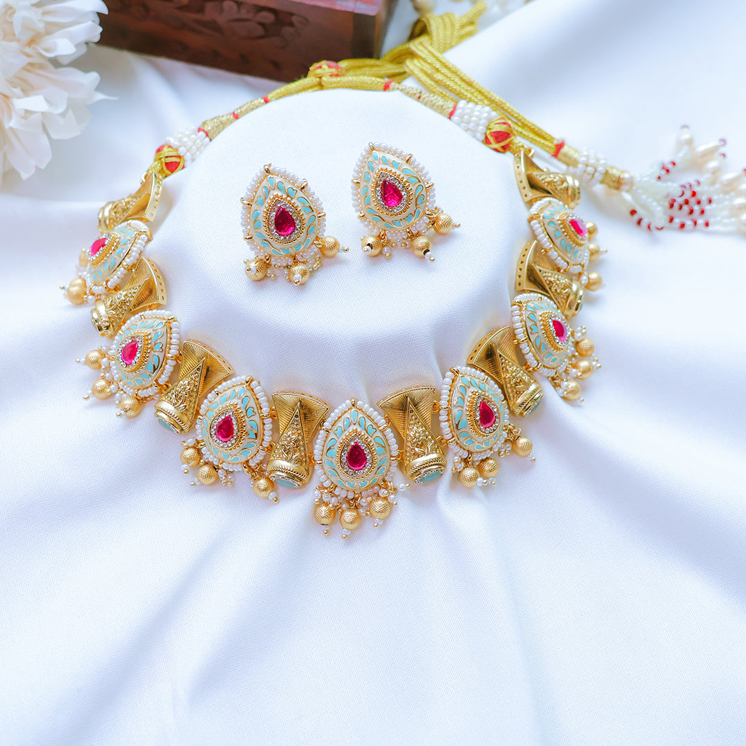 Gold jewelry set with red stones on a white surface