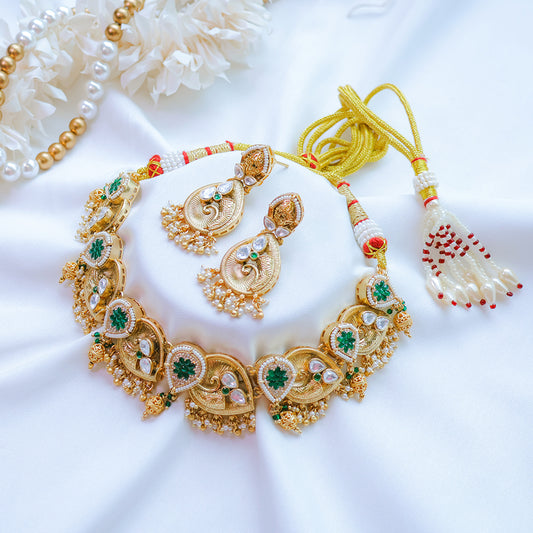 Gold necklace with green gemstones and matching earrings on a white background