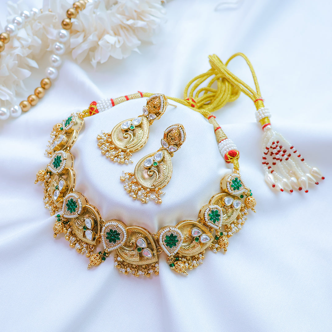 Gold necklace with green gemstones on a white background