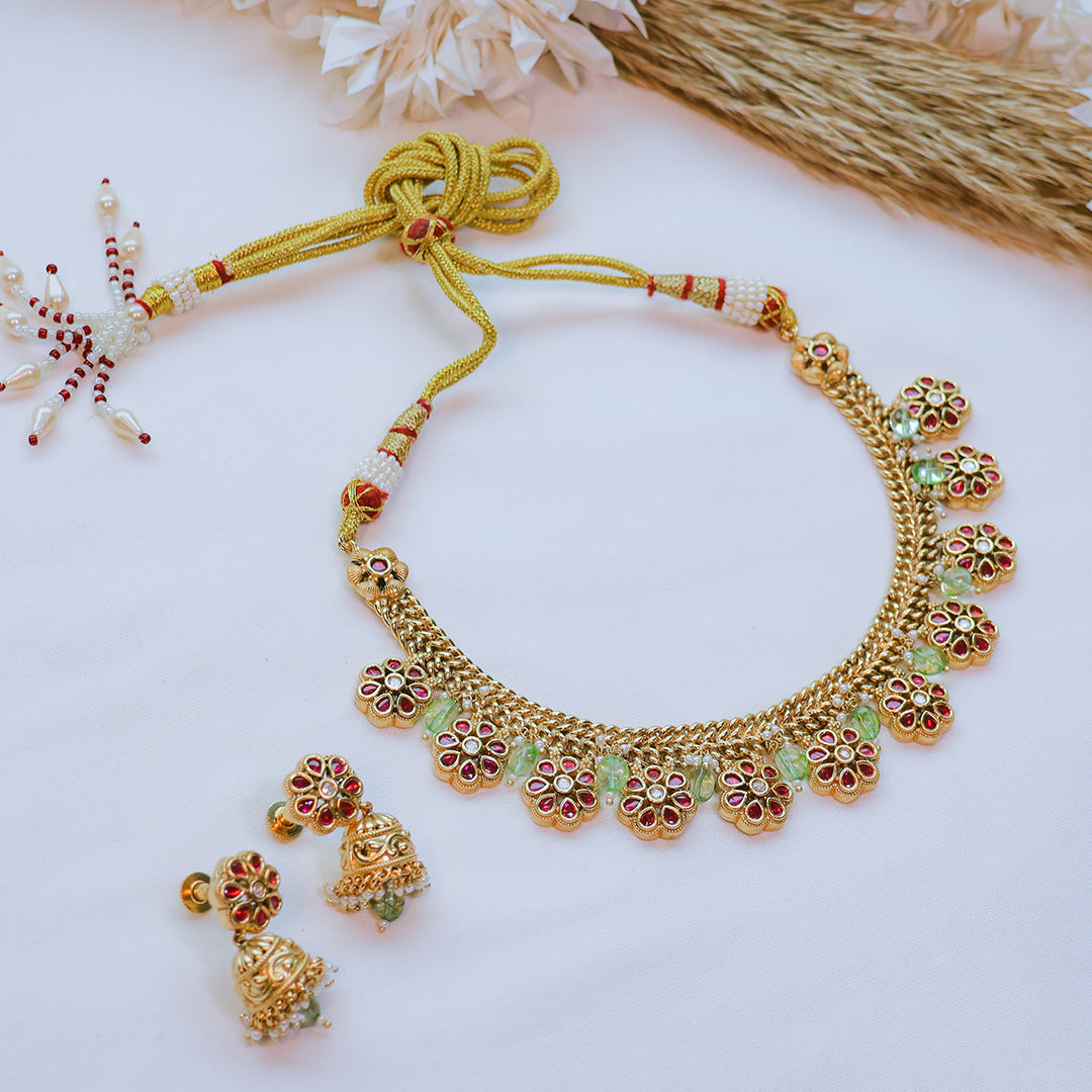 Gold necklace with floral designs on a light background