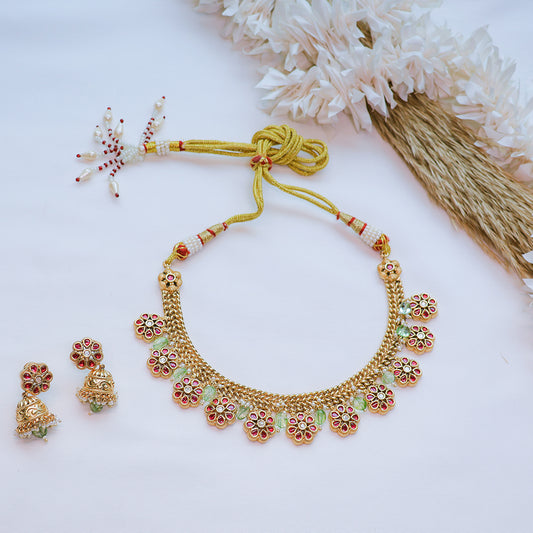 Gold necklace with floral designs and matching earrings on a white background