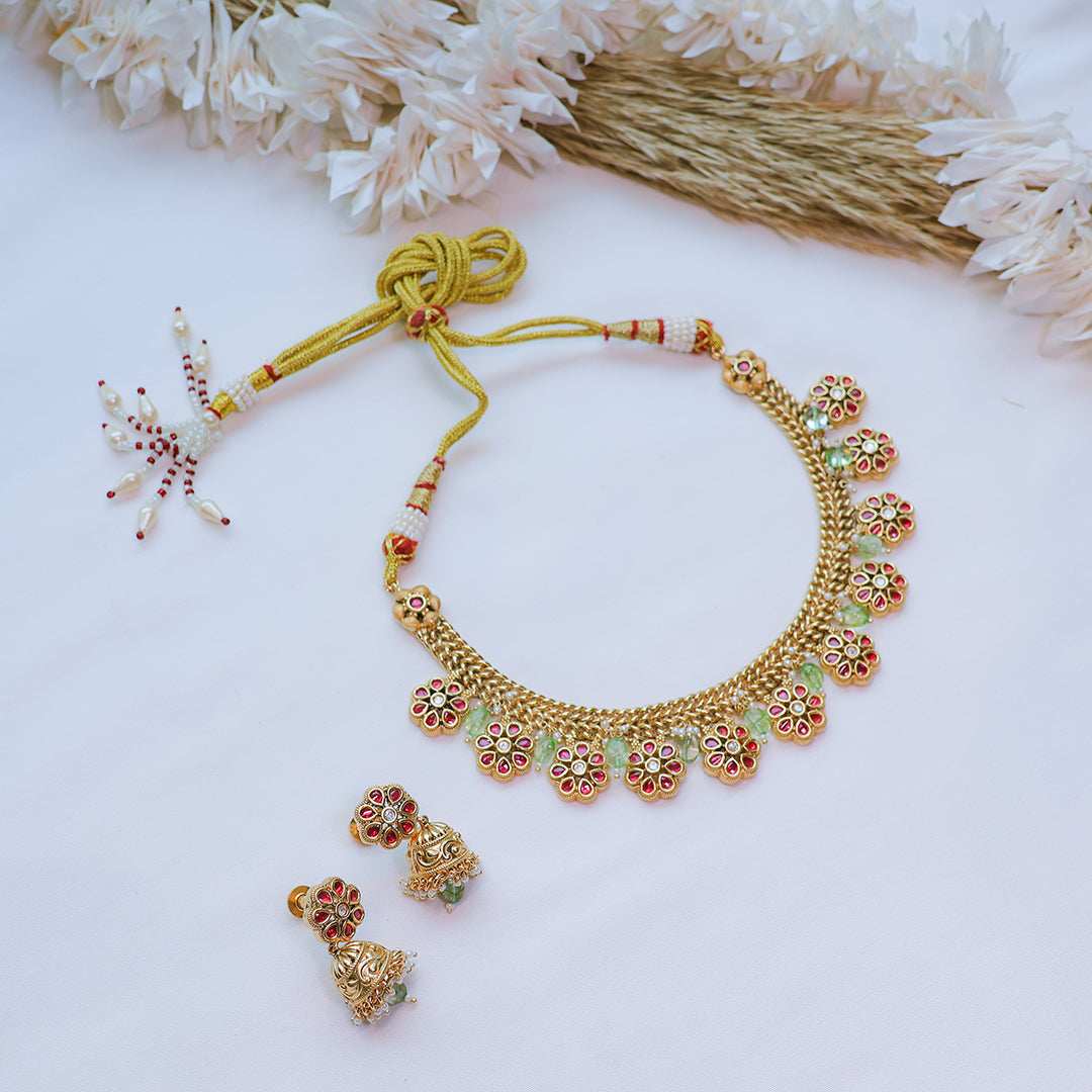 Gold necklace and earrings set on a white background with decorative elements.