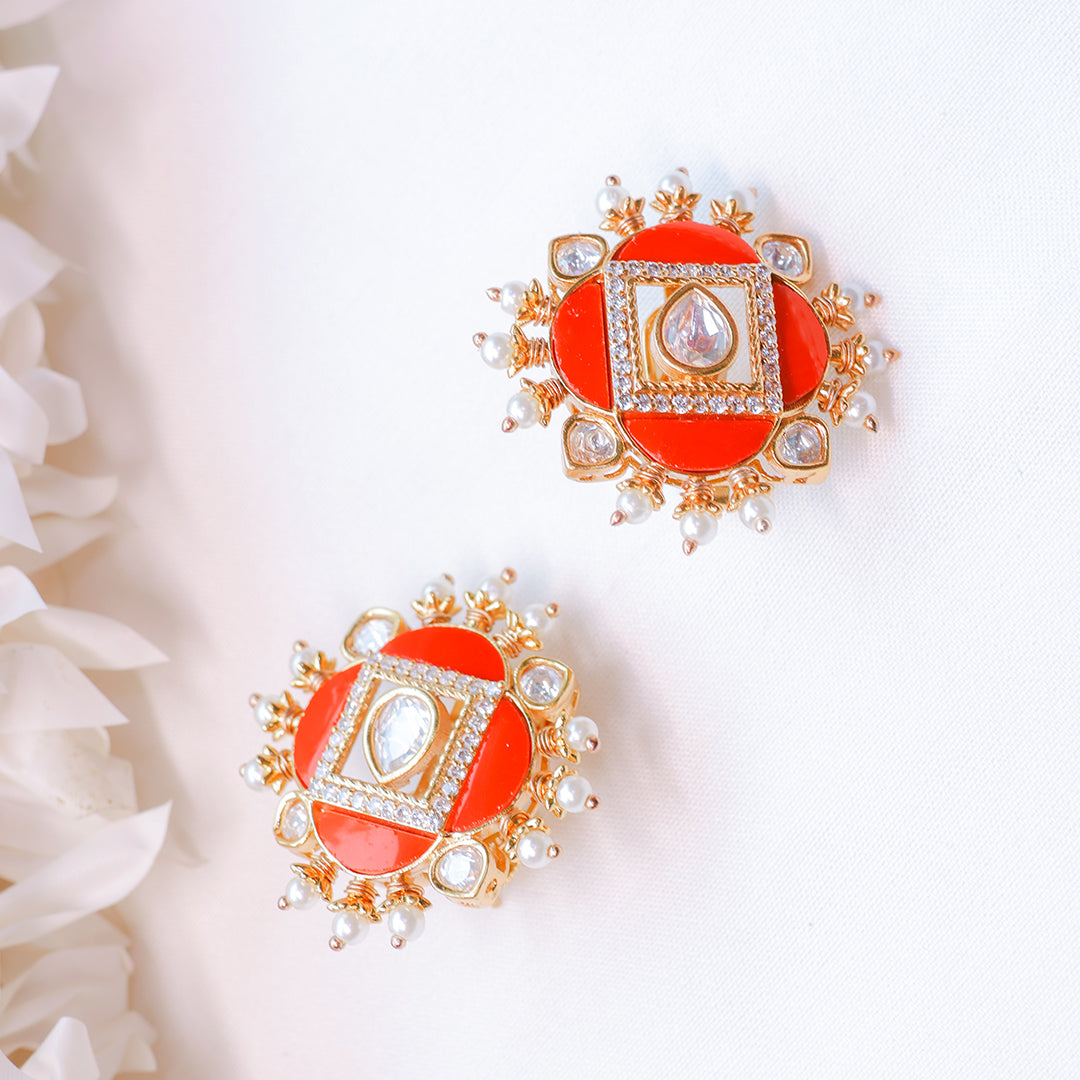 Pair of red earrings with gold and pearl accents on a white background