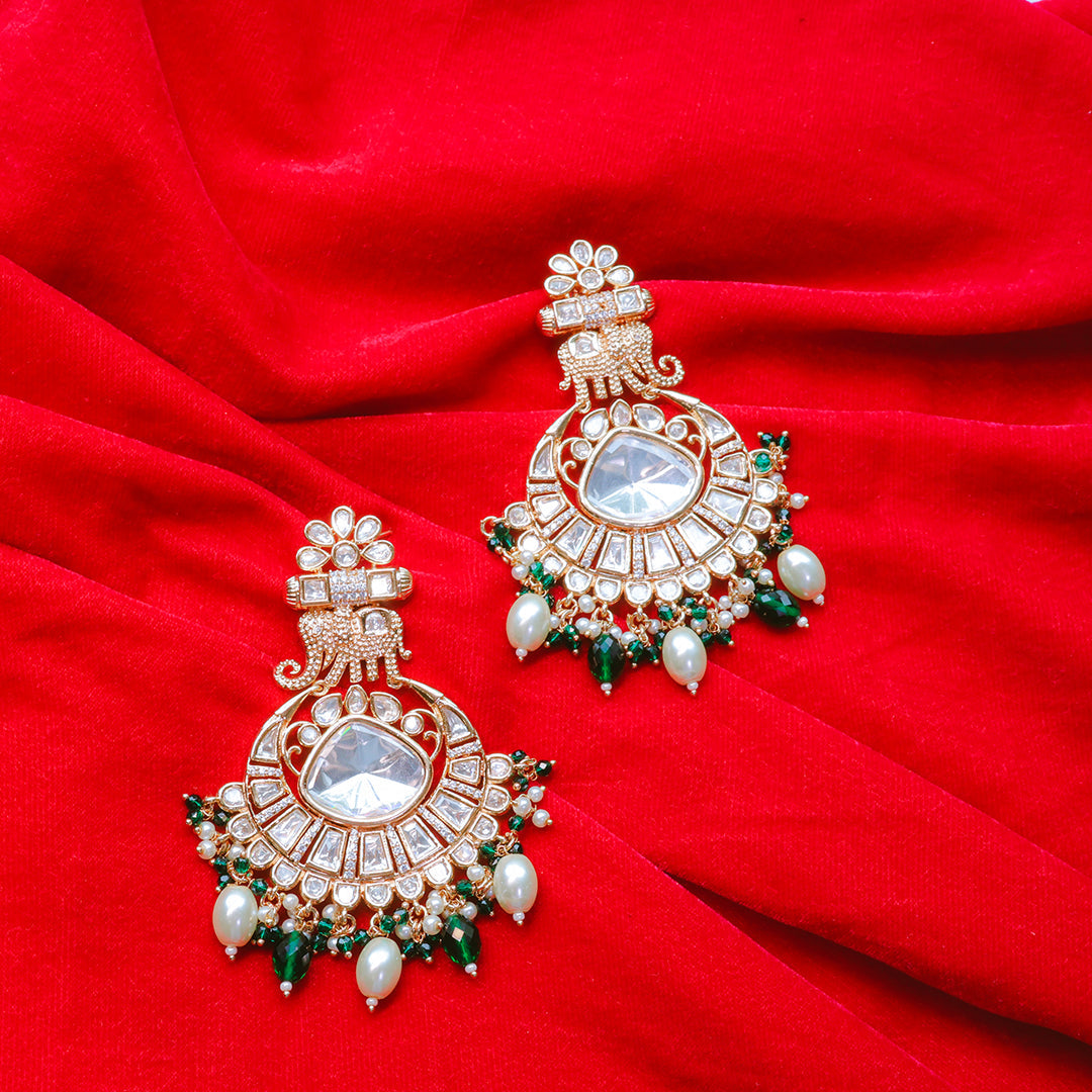 Ornate earrings with green and red accents on a red fabric background
