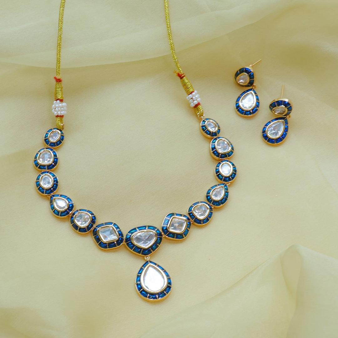 Jewelry set with necklace, earrings, and rakhi on a light yellow fabric background