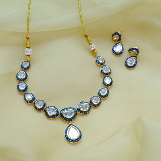 Jewelry set with necklace, earrings, and rakhi on a light yellow fabric background