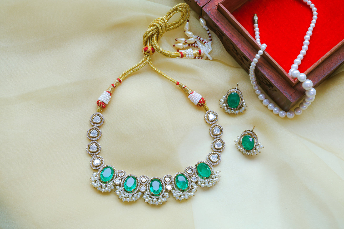 Jewelry set with emerald green stones on a beige surface