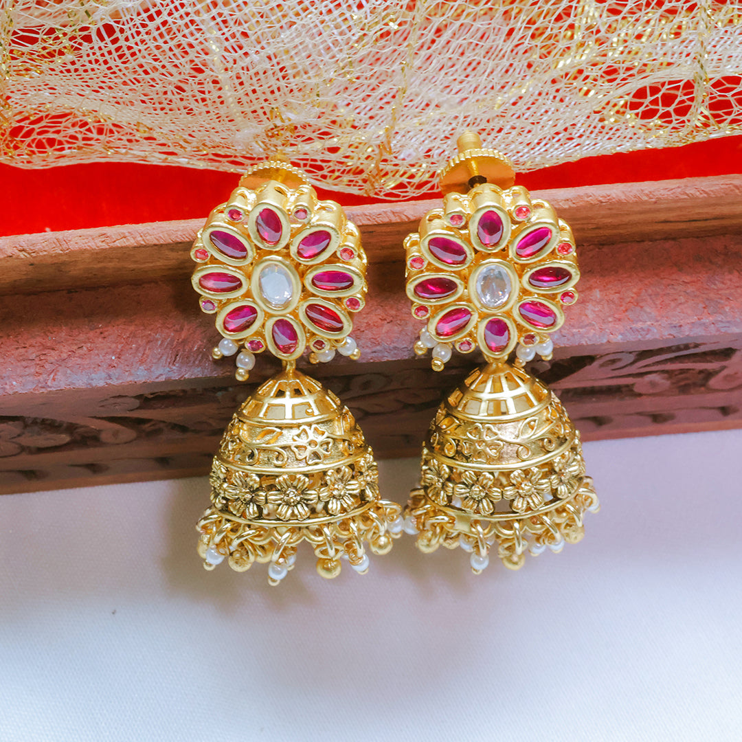 Gold and pink earrings on a decorative background