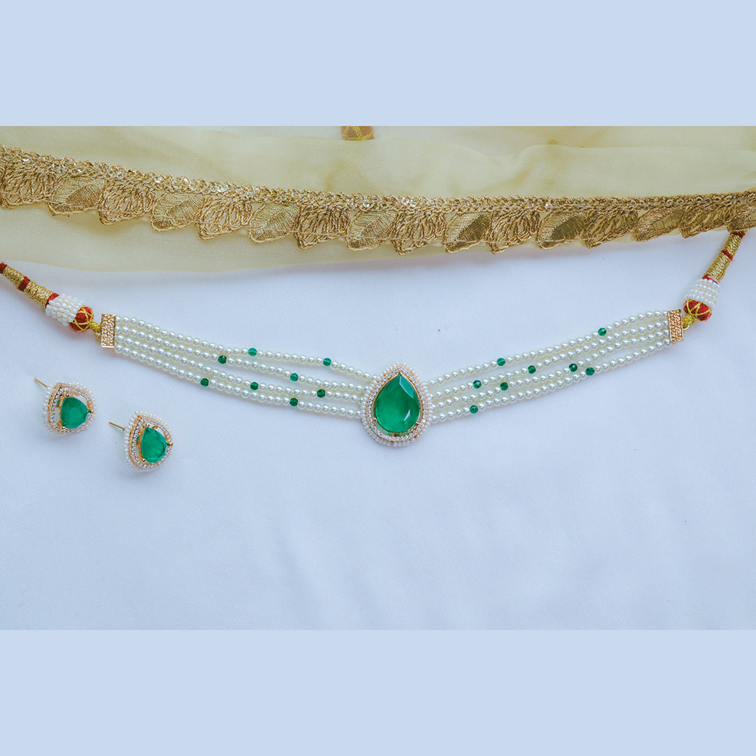 Jewelry set with necklace and earrings featuring green stones on a light background
