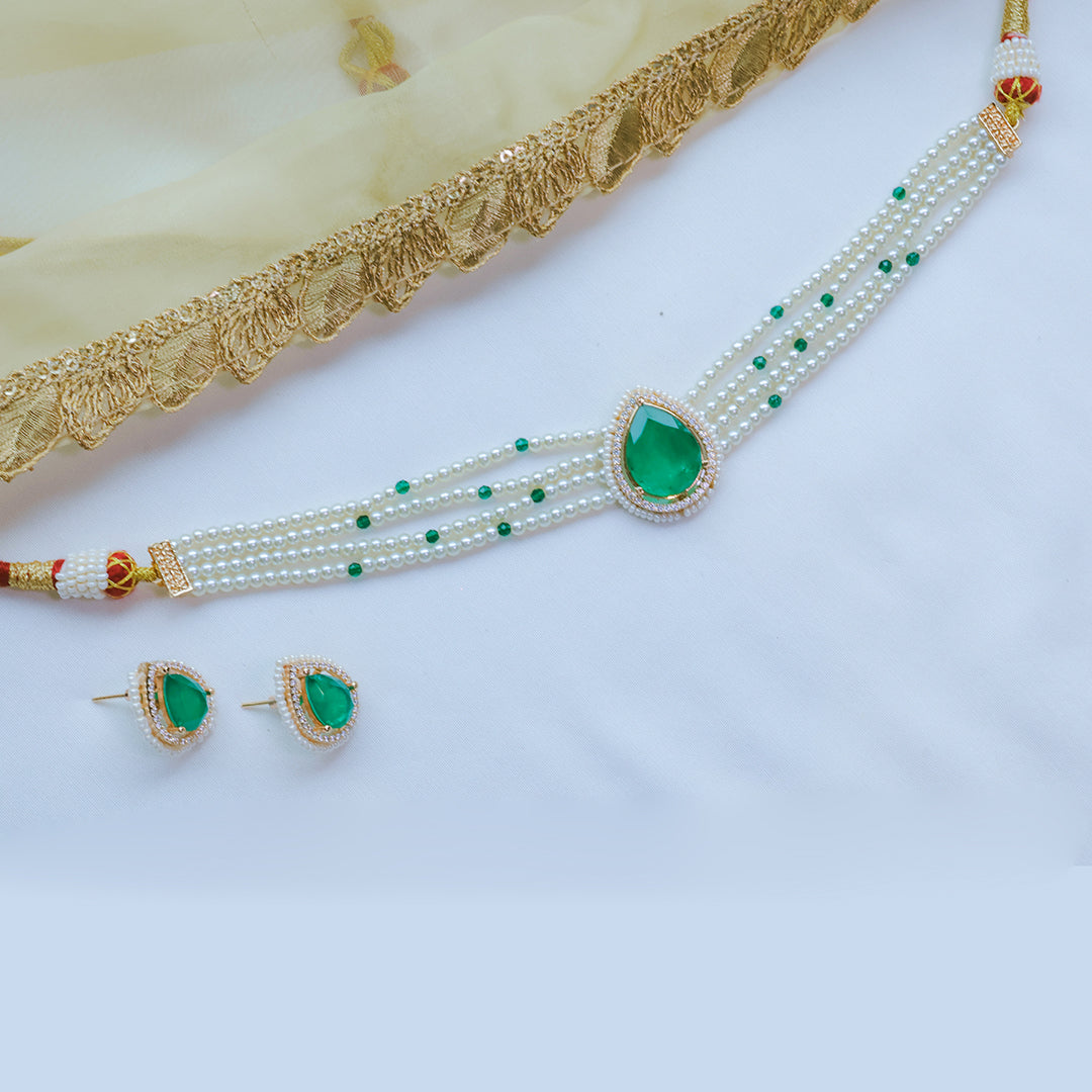 Pearl necklace with green teardrop pendants and matching earrings on a white background.