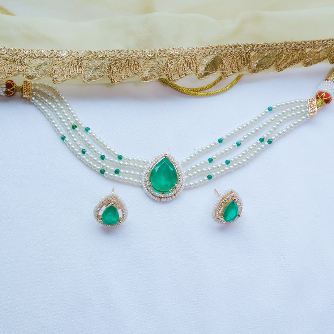 Jewelry set with necklace and earrings featuring green teardrop pendants on a white background.