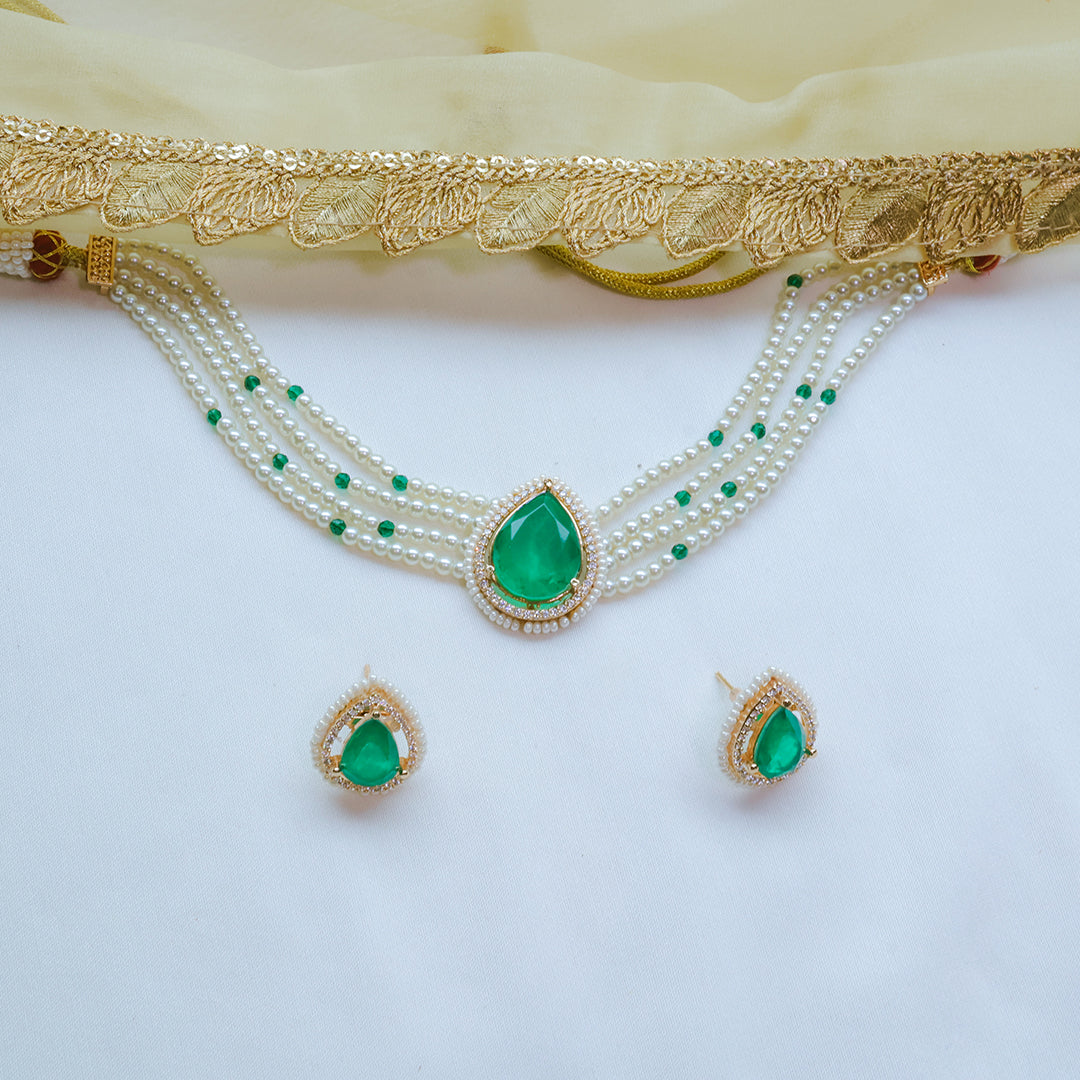 Jewelry set with green gemstones and gold accents on a white background