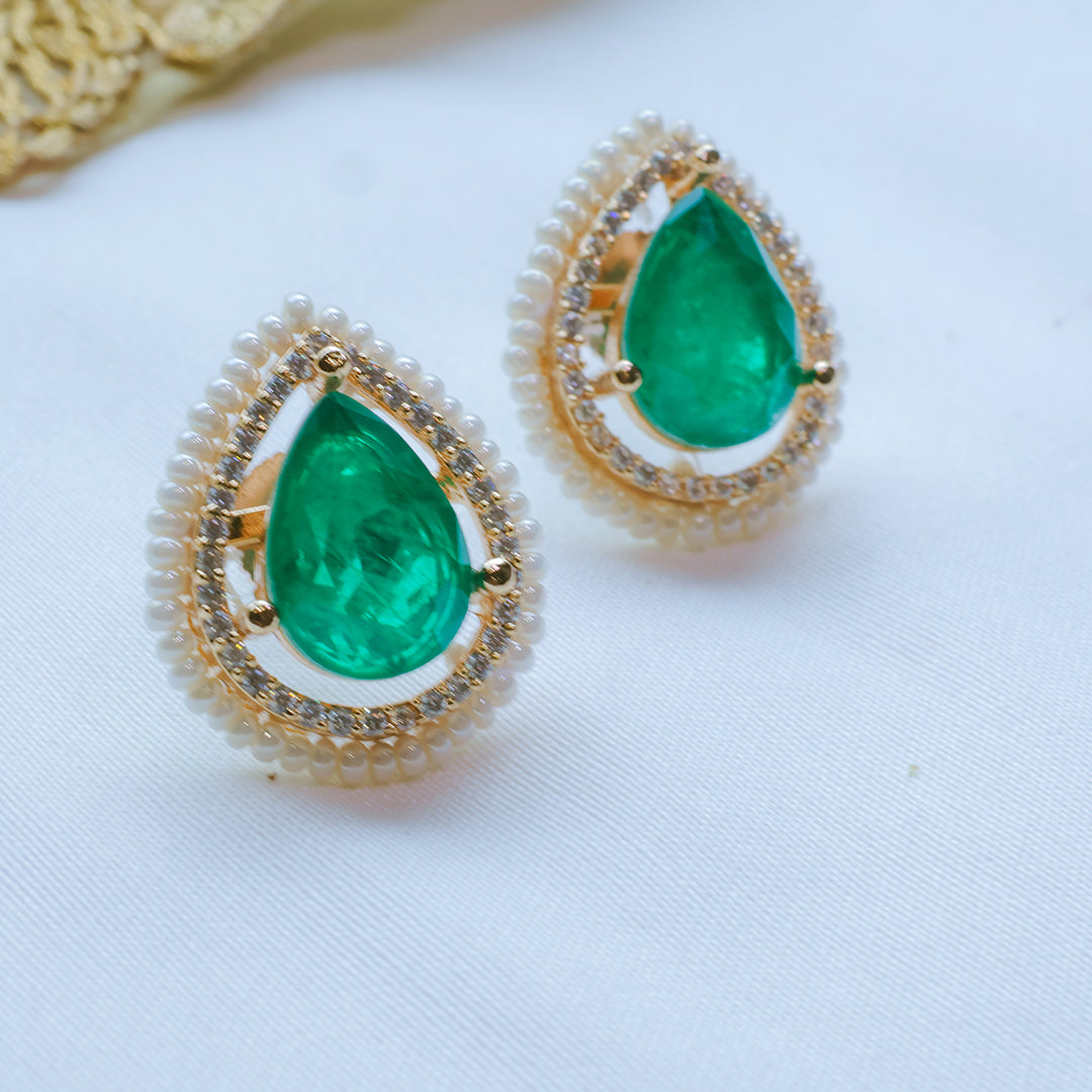 Gold earrings with green teardrop stones on a white background
