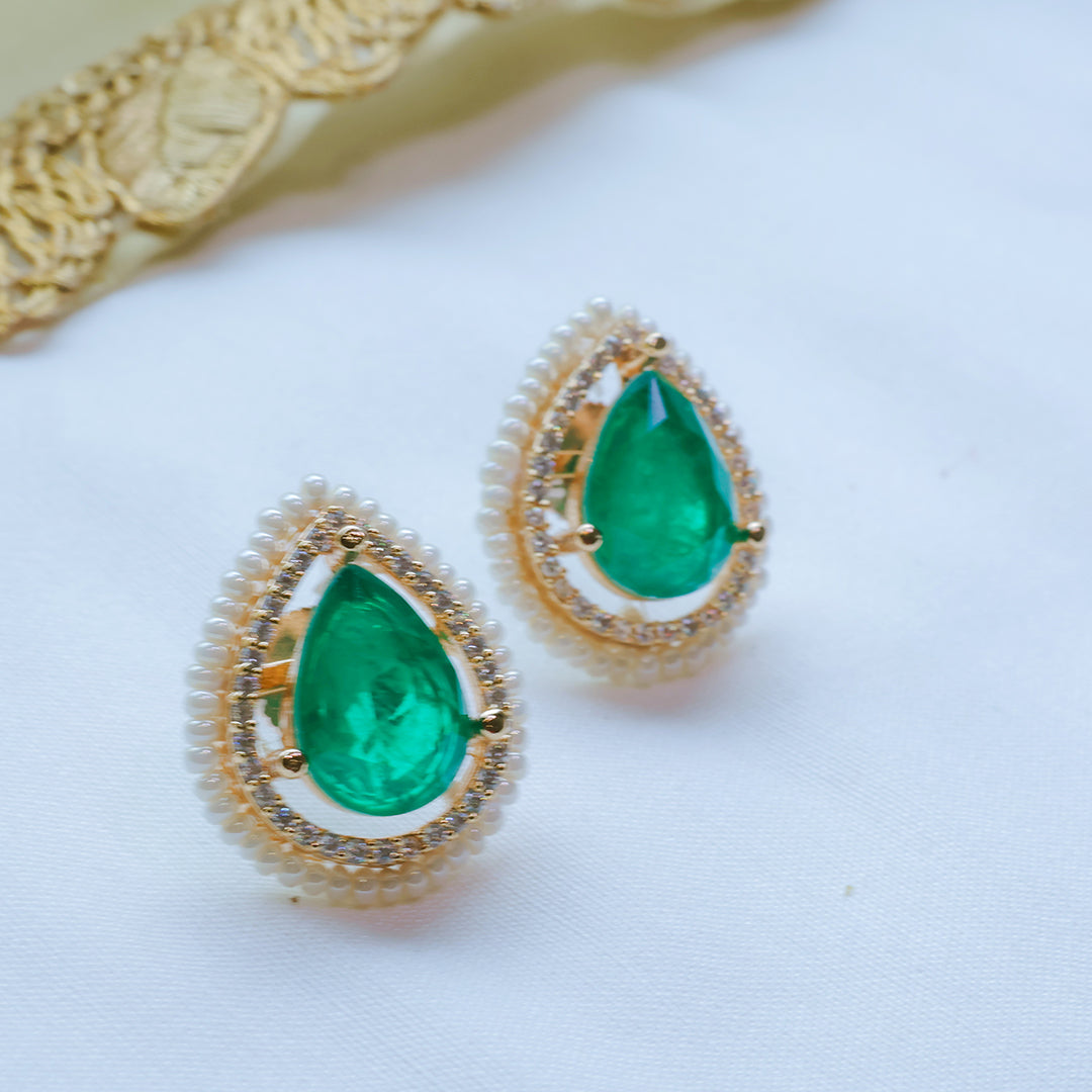 Gold earrings with green gemstones on a white background