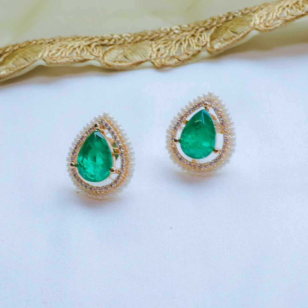Gold earrings with green gemstones on a white background