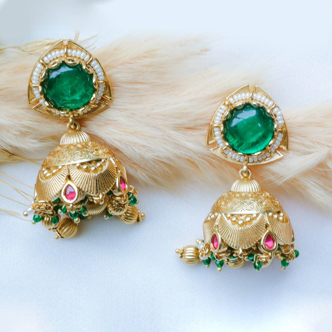 Gold earrings with green and red gemstones on a white background