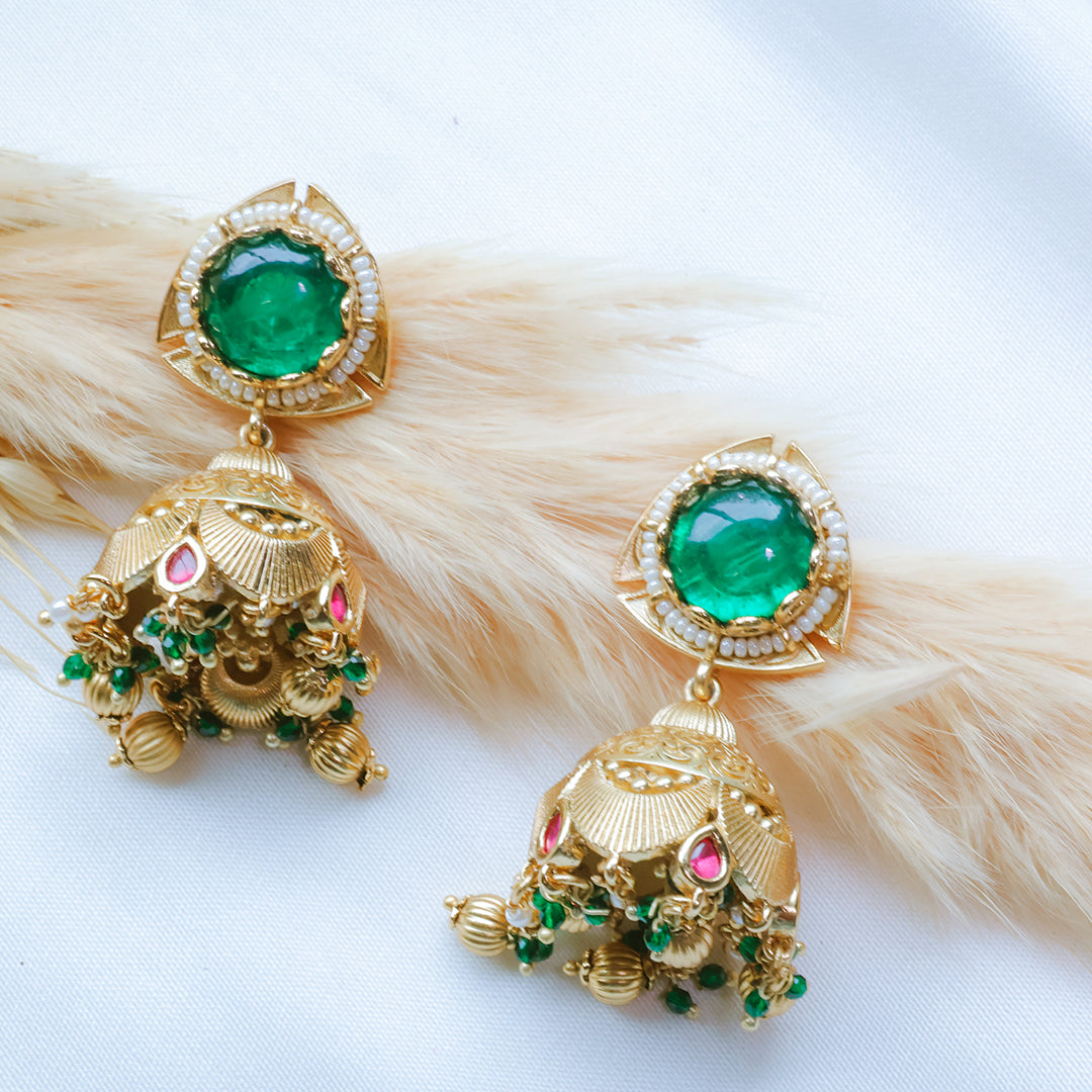 Gold earrings with green and pink gemstones on a white background