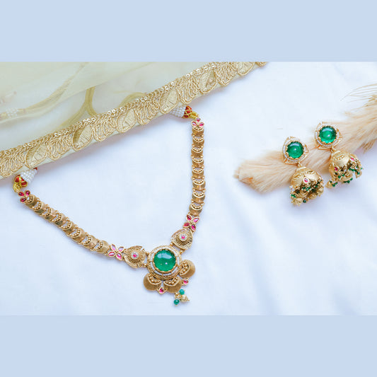 Gold necklace with green gemstones and matching earrings on a white background