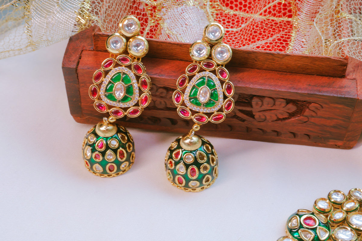 Ornate earrings with green, red, and gold colors on a white surface.