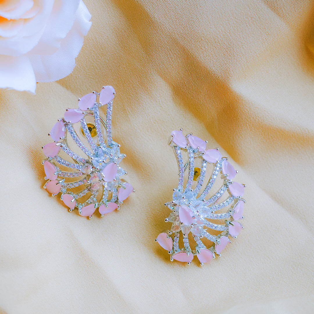 Pair of pink and silver earrings on a beige fabric background