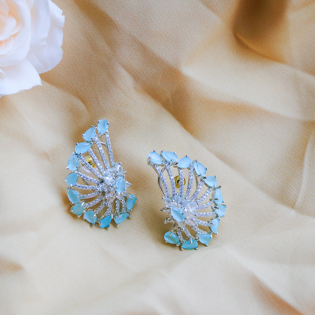 Pair of earrings with blue gemstones on a beige fabric background