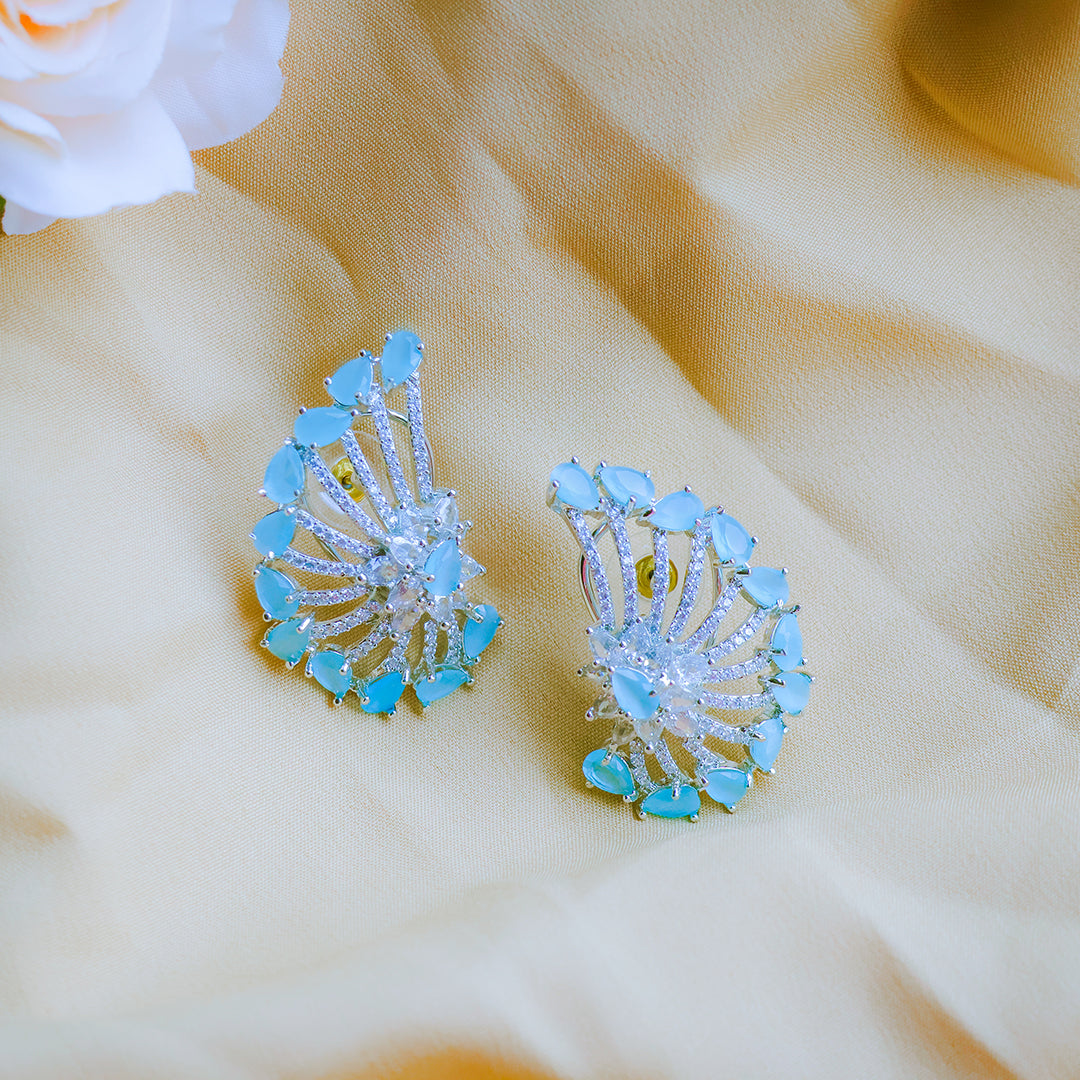 Pair of blue and silver earrings on a beige fabric background
