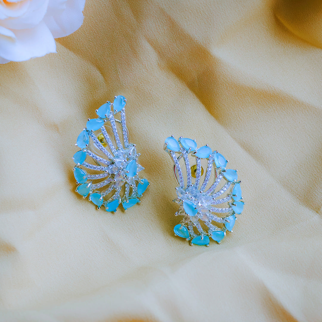 Pair of blue gemstone earrings on a beige fabric background