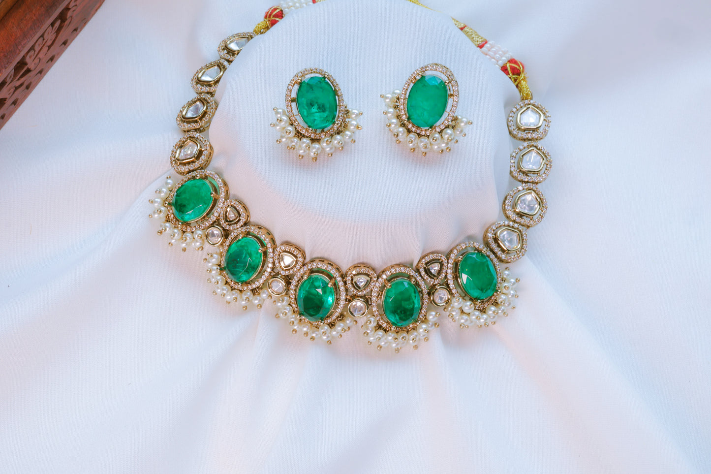 Jewelry set with emerald green stones on a white background