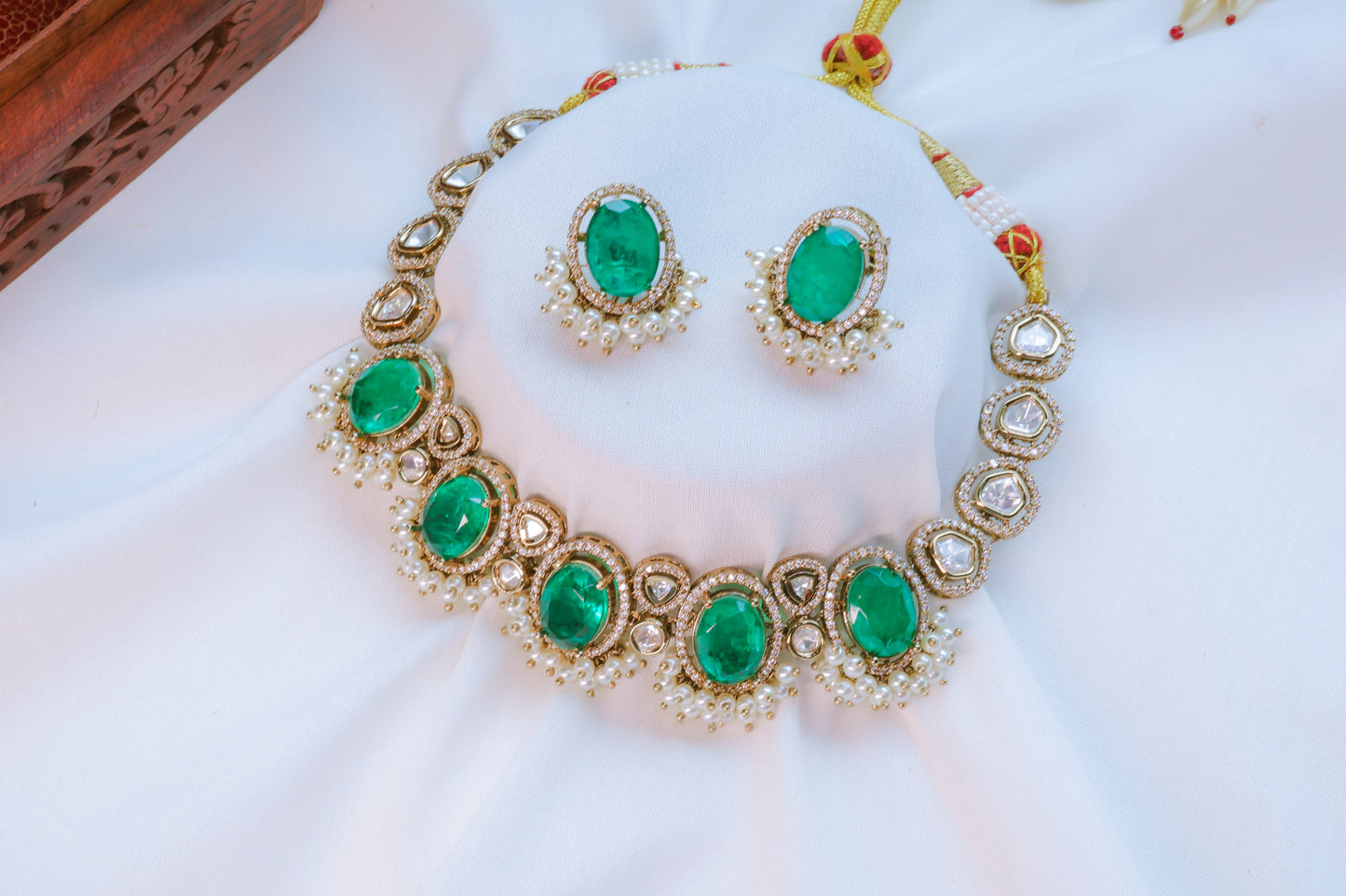 Jewelry set with emerald green stones on a white fabric background