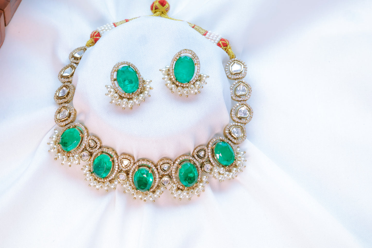 Jewelry set with emerald green stones on a white background