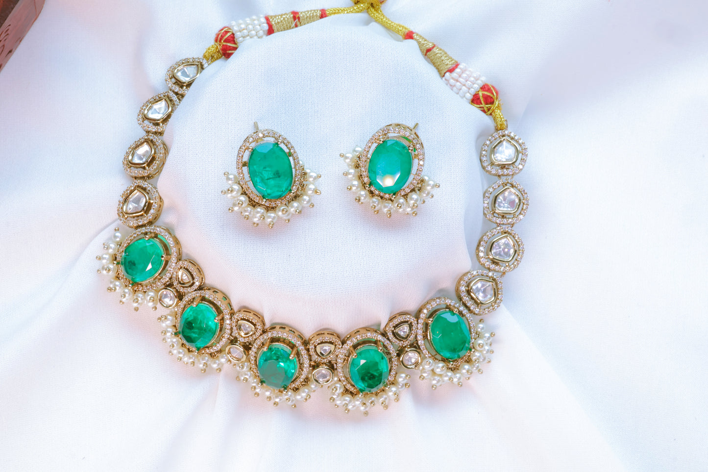 Jewelry set with emerald green stones on a white background