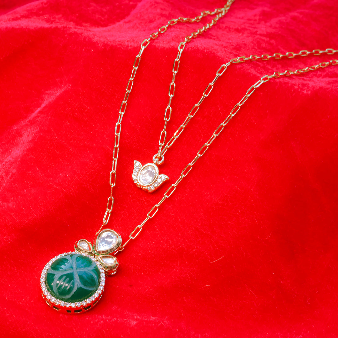 Gold necklace with green pendant on a red background