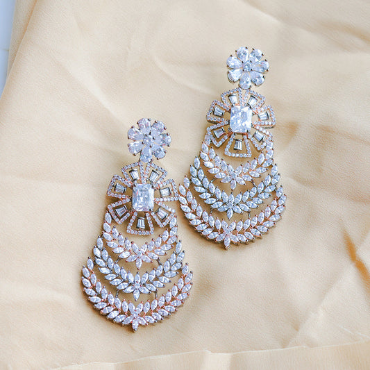 Pair of ornate earrings with gemstones on a beige fabric background