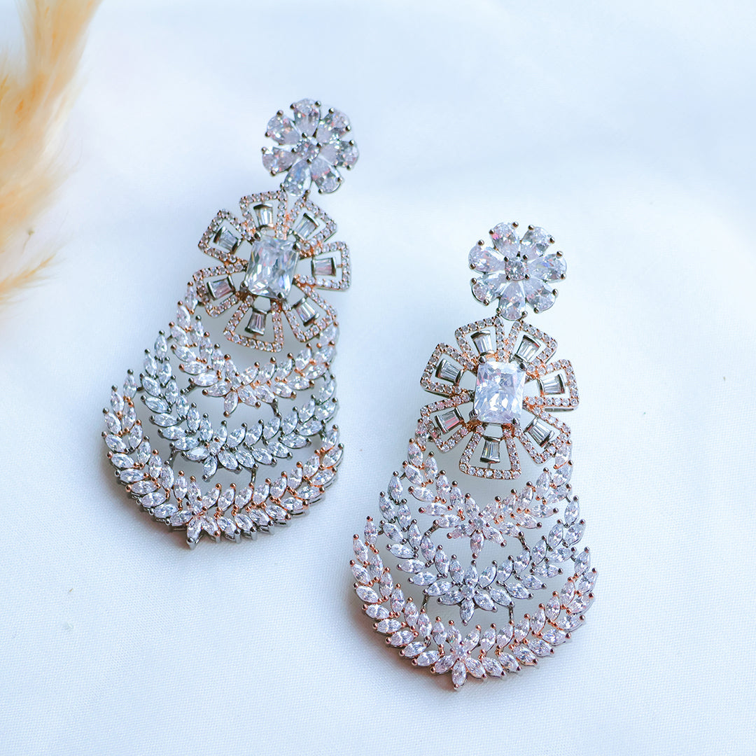 Pair of ornate earrings with clear gemstones on a light background