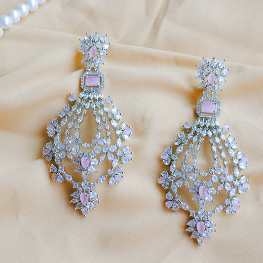 Pair of chandelier earrings with pink gemstones on a beige fabric background