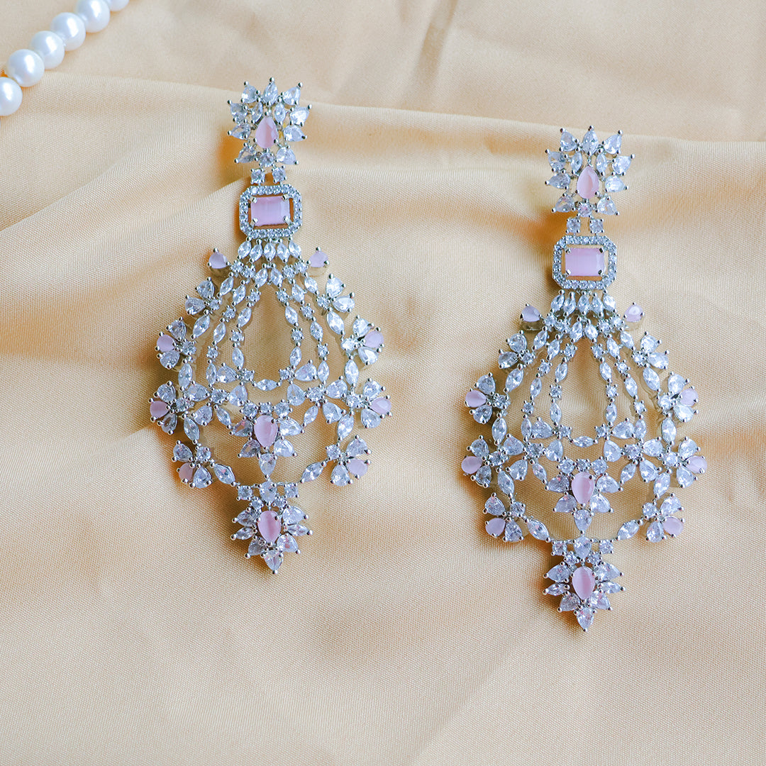 Pair of chandelier earrings with pink gemstones on a beige fabric background