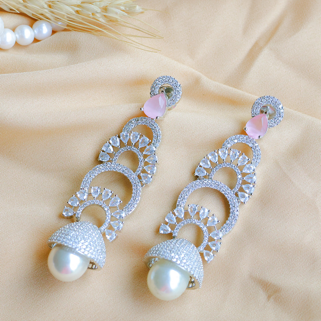 Elegant silver earrings with pearls on a beige fabric background