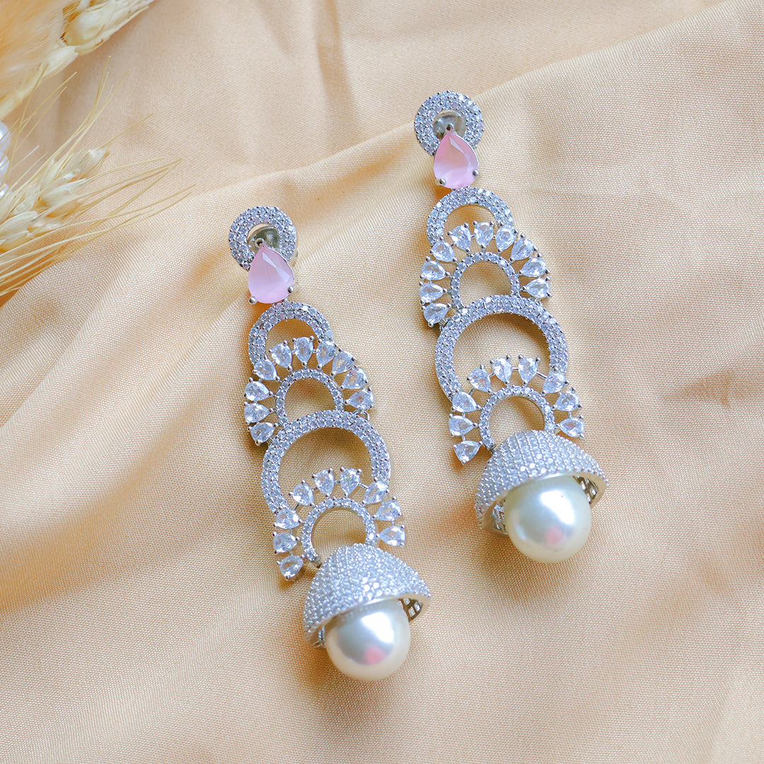 Ornate silver earrings with pearls on a beige fabric background