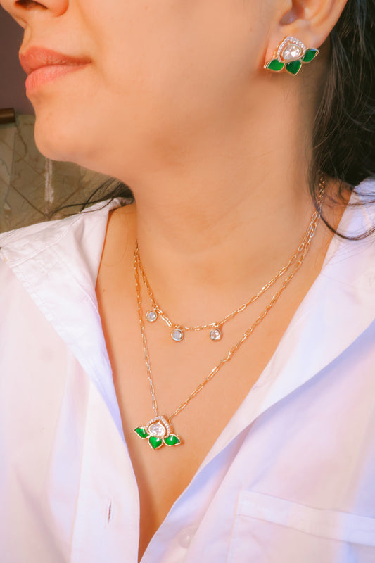 Close-up of a person wearing gold necklaces and earrings with floral designs.