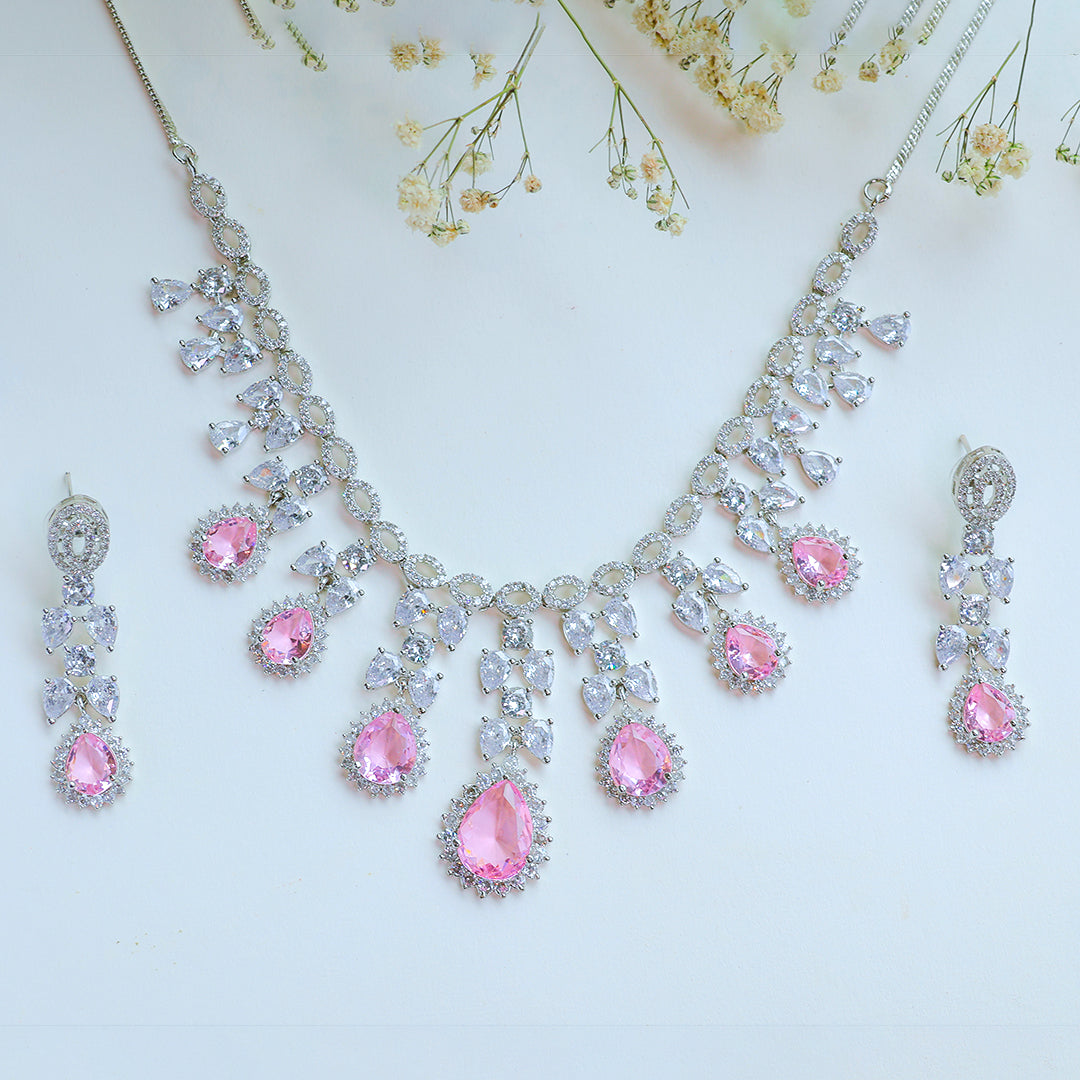 Necklace and earrings with pink gemstones on a light background