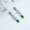 Earrings with green and clear gemstones on a light background