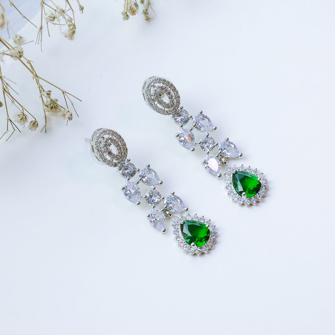Earrings with green and clear gemstones on a light background