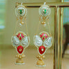 Ornate earrings with red, green, and gold colors on a stand.