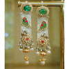 Ornate gold earrings with green and red gemstones on a blurred background